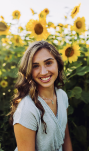 A woman smiling in a field of sunflowers. 